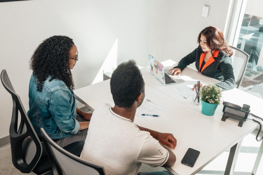 Couple sitting at table with realtor | Benefits of Using a Realtor | Home Interiors | Elle Blonde Luxury Lifestyle Destination Blog